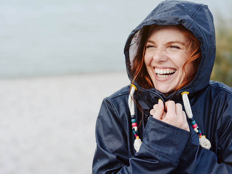 Laughing woman on beach in rain.